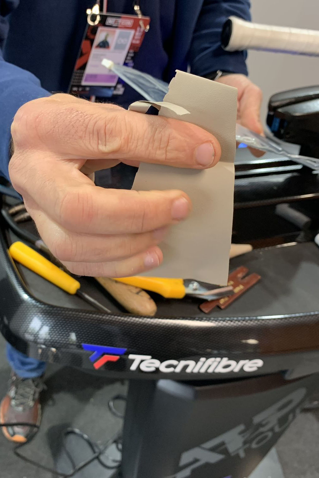 Incordatore mostra il tessuto integratore sensoriale di Alfio Caronti prima di applicarlo alla racchetta di Jannik Sinner